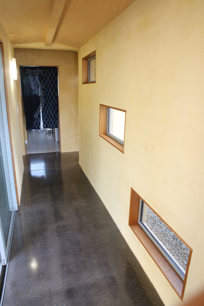 Пример оригинального дизайна: маленький коридор в современном стиле с желтыми стенами и бетонным полом для на участке и в саду