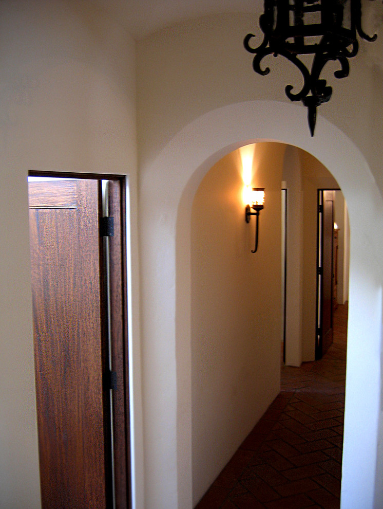 На фото: коридор среднего размера в средиземноморском стиле с белыми стенами, полом из терракотовой плитки и красным полом с