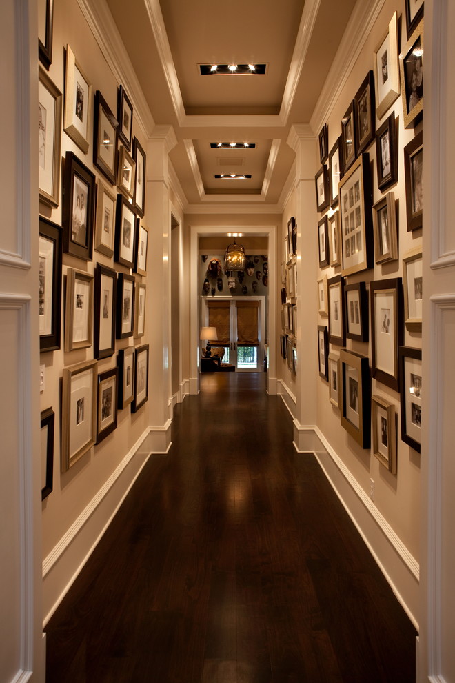 На фото: огромный коридор в стиле неоклассика (современная классика) с бежевыми стенами, темным паркетным полом и коричневым полом с