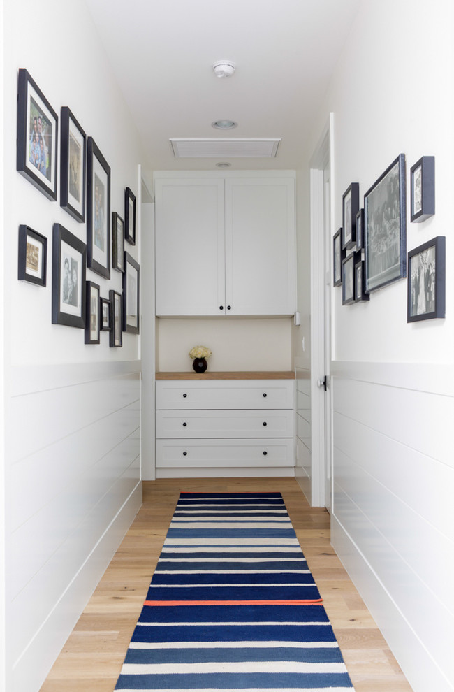 Idée de décoration pour un couloir tradition avec un mur blanc et un sol en bois brun.