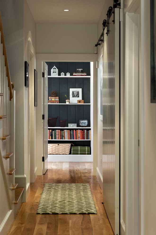 Example of a mid-sized classic medium tone wood floor hallway design in Portland Maine with white walls