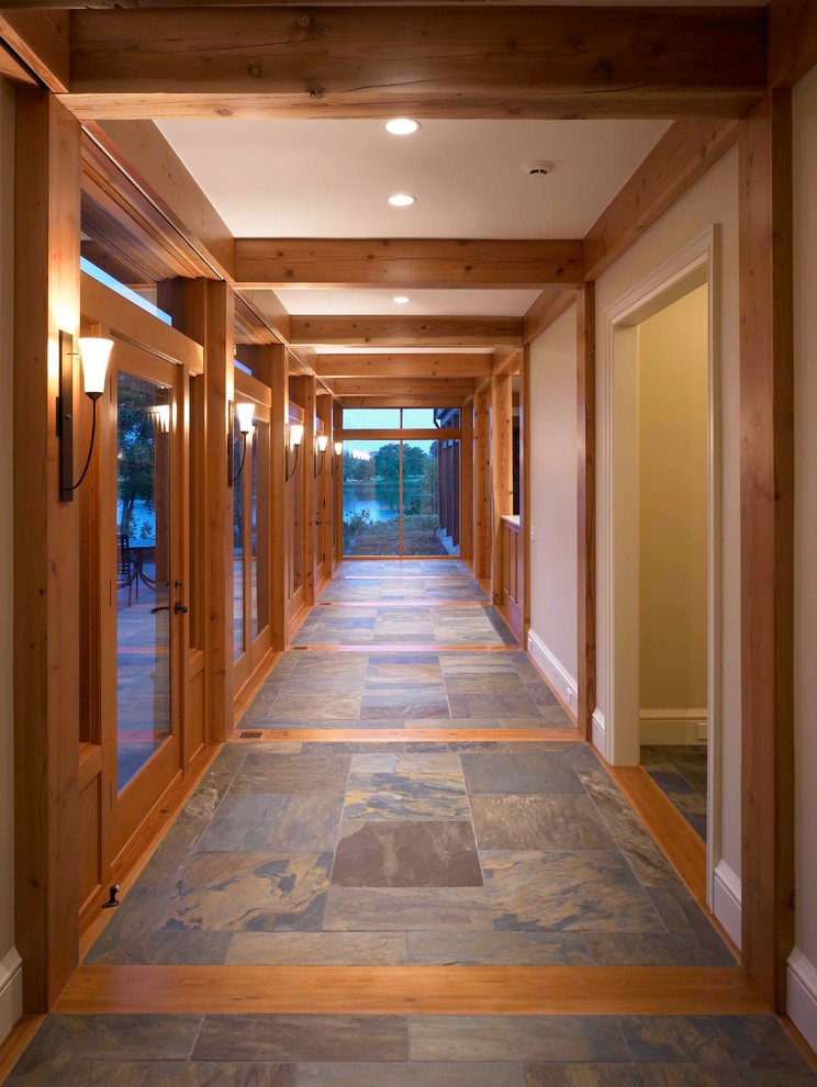 На фото: огромный коридор в стиле рустика с белыми стенами, полом из сланца и разноцветным полом с