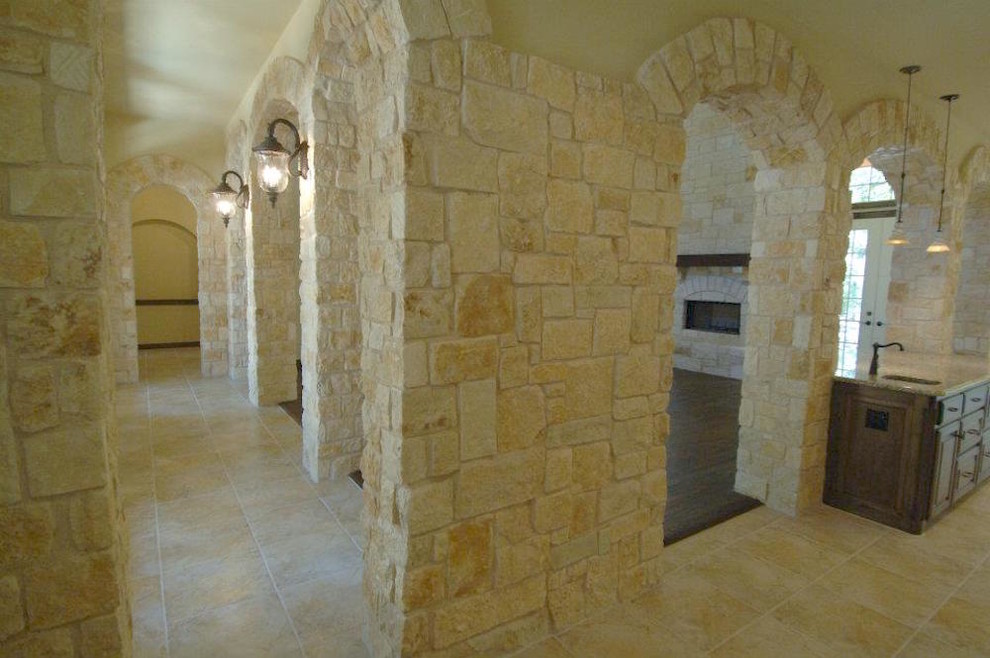 На фото: большой коридор в классическом стиле с бежевыми стенами, полом из керамической плитки и бежевым полом с