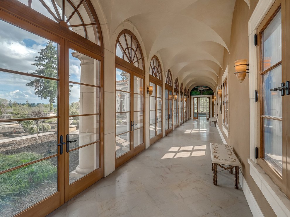 На фото: большой коридор в классическом стиле с коричневыми стенами, мраморным полом и бежевым полом с