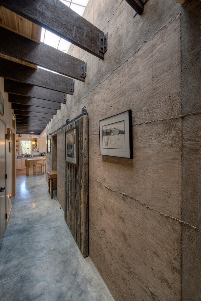 Imagen de recibidores y pasillos rústicos con suelo de cemento, paredes marrones y iluminación