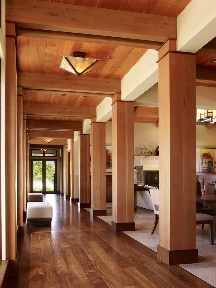 Cette image montre un grand couloir design avec un sol en bois brun, un mur beige et un sol marron.