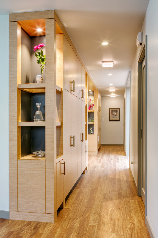 Cette photo montre un couloir moderne en bois de taille moyenne avec un mur marron, un sol en vinyl, un sol marron et un plafond voûté.