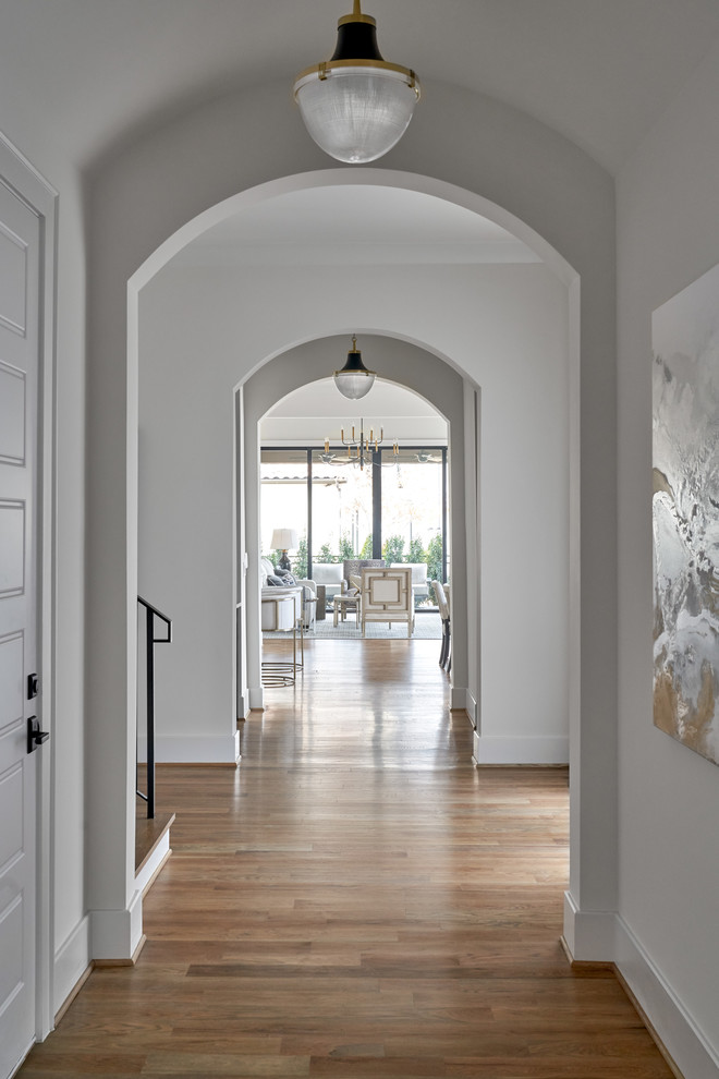 ダラスにある中くらいなトランジショナルスタイルのおしゃれな廊下 (白い壁、無垢フローリング、ベージュの床) の写真