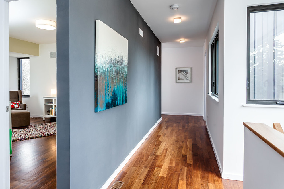 Aménagement d'un couloir contemporain de taille moyenne avec un mur gris et un sol en bois brun.