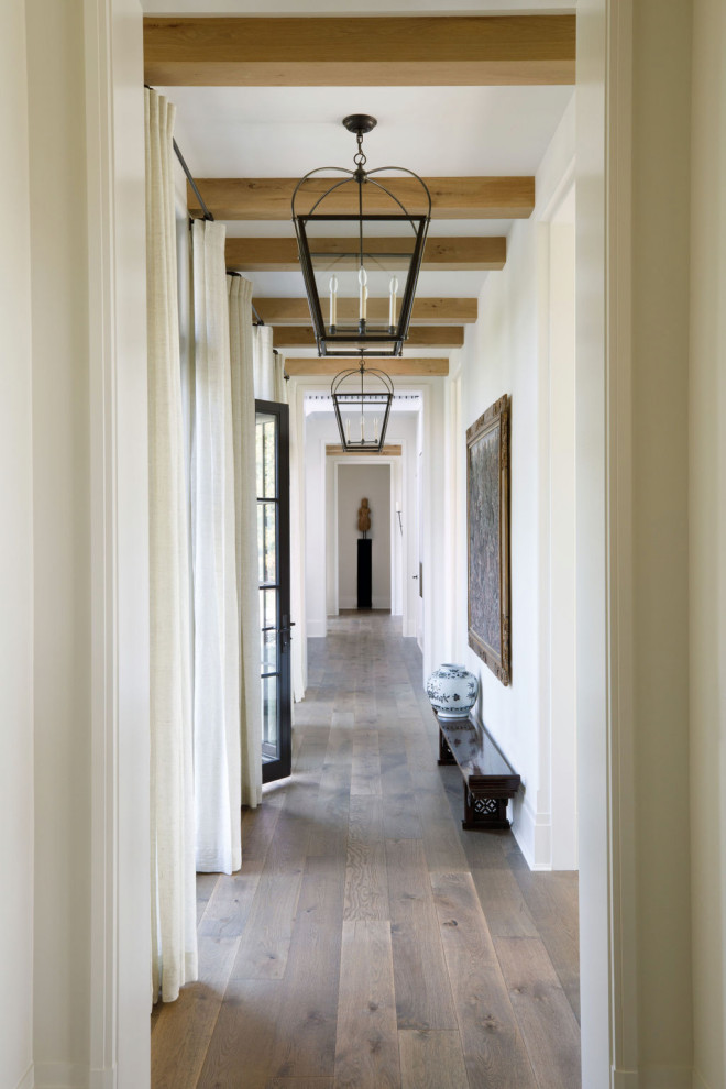 Modelo de recibidores y pasillos tradicionales extra grandes con paredes beige, suelo de madera en tonos medios, suelo marrón y vigas vistas