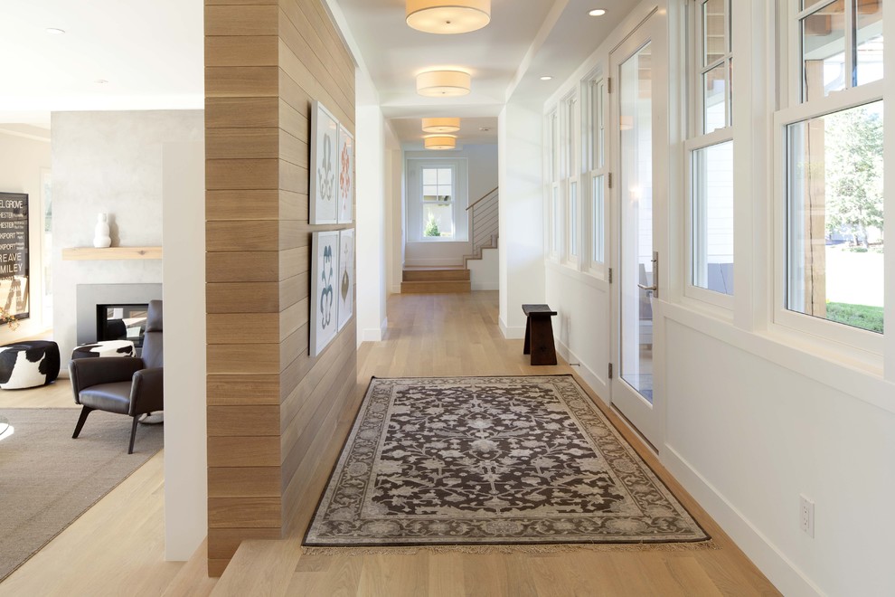 Ispirazione per un ingresso o corridoio design con pareti bianche, pavimento in legno massello medio e pavimento beige