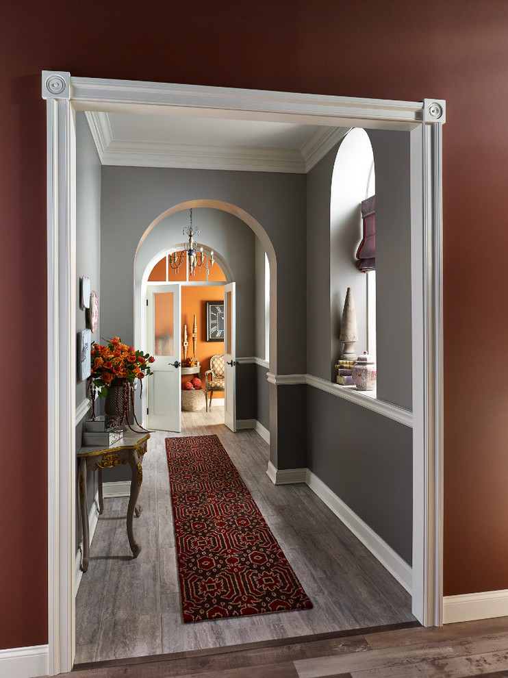 Cette photo montre un couloir chic avec un mur gris, un sol en bois brun et un sol marron.