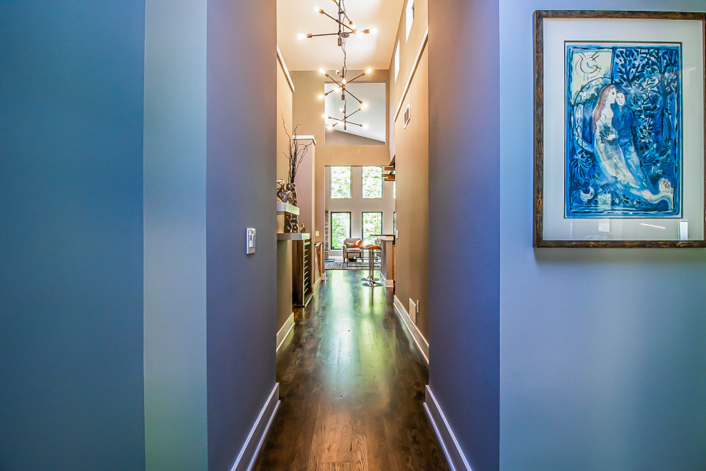 Exemple d'un très grand couloir chic avec un mur bleu, parquet foncé et un sol marron.