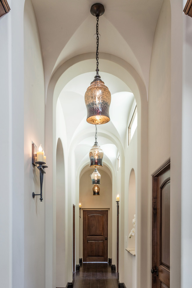 Пример оригинального дизайна: коридор в средиземноморском стиле с белыми стенами, темным паркетным полом и коричневым полом