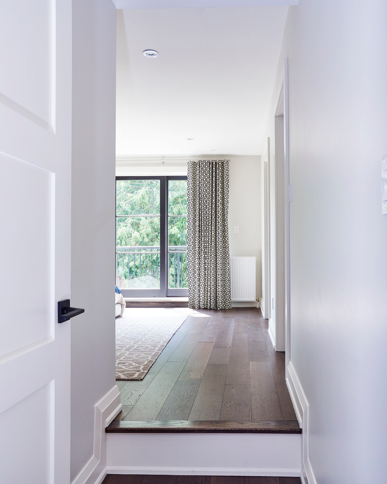 Idées déco pour un couloir classique de taille moyenne avec un mur blanc et un sol en bois brun.