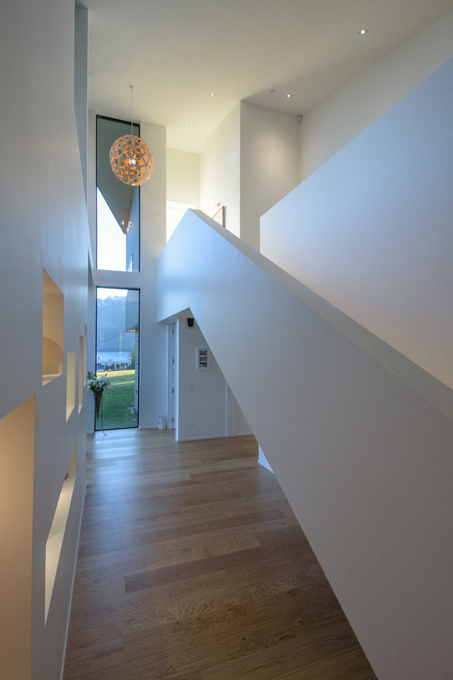 Großer Moderner Flur mit weißer Wandfarbe, braunem Holzboden und braunem Boden in Sonstige