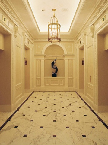Cette photo montre un grand couloir chic avec un mur blanc et un sol en marbre.