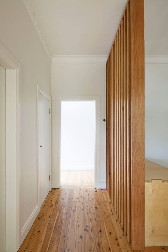 Aménagement d'un petit couloir contemporain avec un mur blanc, un sol en bois brun et un sol marron.