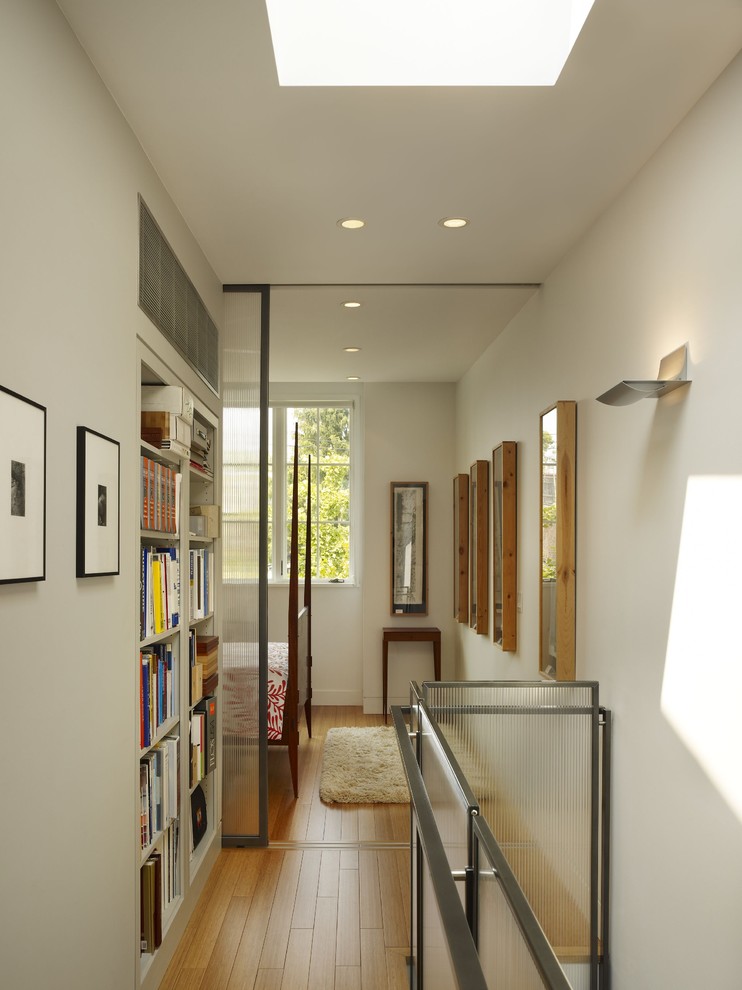 Exemple d'un couloir chic avec un mur blanc et un sol en bois brun.