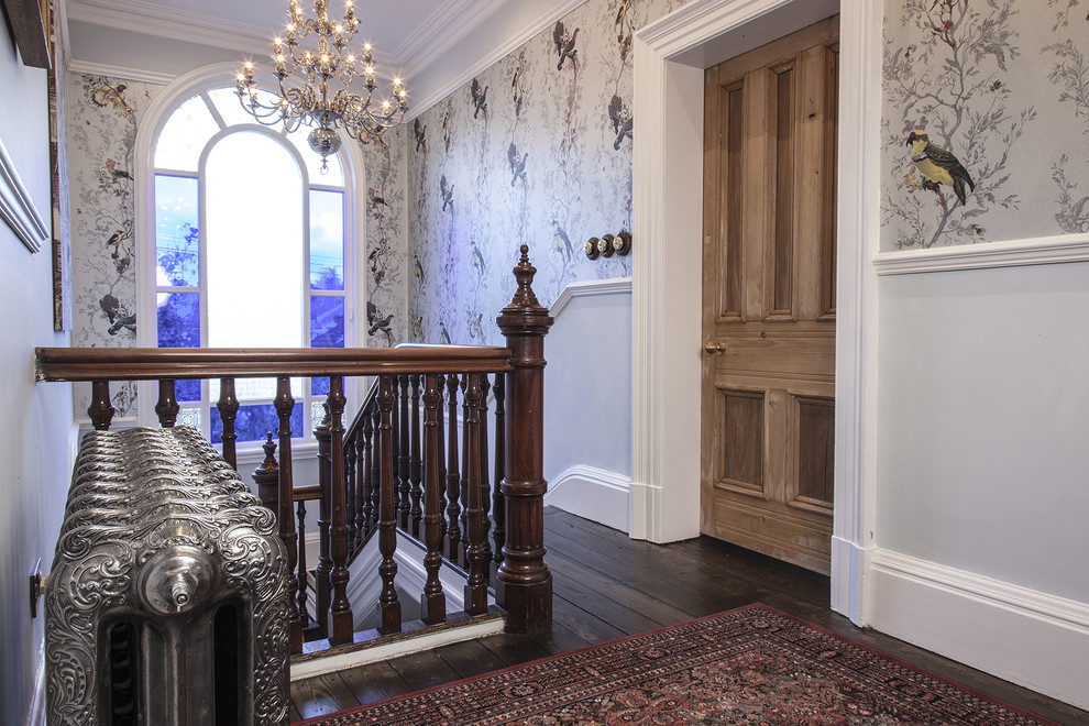 Inspiration pour un couloir traditionnel de taille moyenne avec un mur multicolore, parquet foncé et un sol marron.