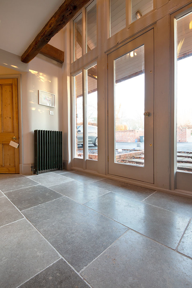 Cette image montre un couloir rustique de taille moyenne avec un sol en calcaire et un sol gris.