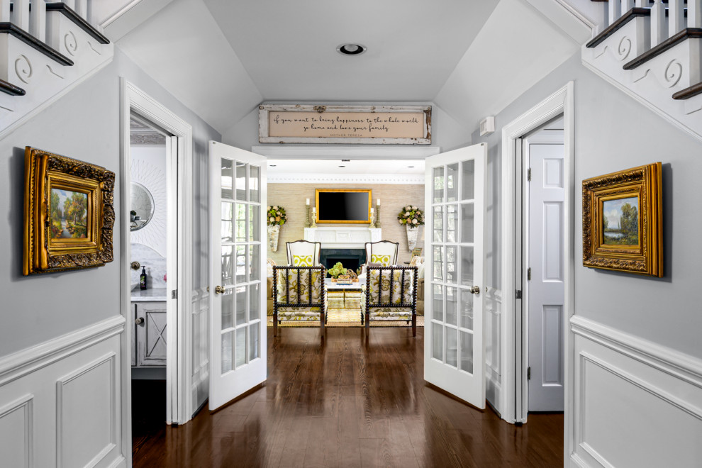 Inspiration for a mid-sized timeless dark wood floor, brown floor, vaulted ceiling and wainscoting hallway remodel in Charlotte with gray walls