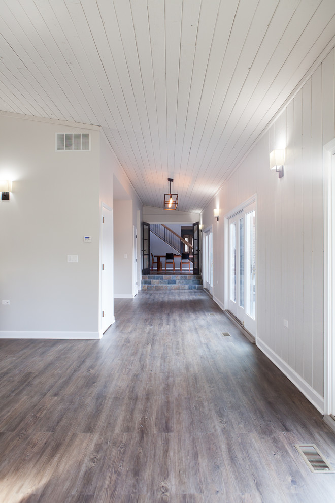 На фото: огромный коридор в стиле неоклассика (современная классика) с серыми стенами и темным паркетным полом