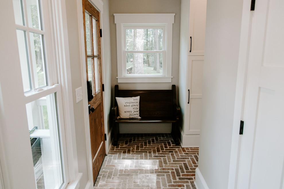На фото: коридор в стиле кантри с серыми стенами, кирпичным полом и коричневым полом