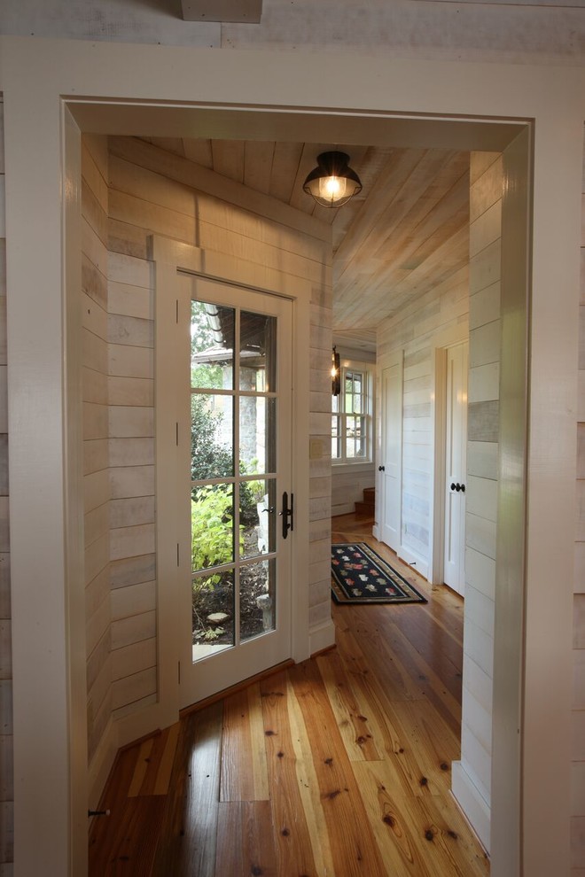 Idée de décoration pour un couloir chalet de taille moyenne avec un mur blanc et un sol en bois brun.