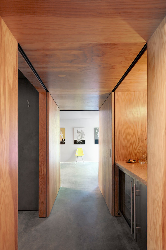Bild på en mellanstor funkis hall, med bruna väggar, betonggolv och grått golv
