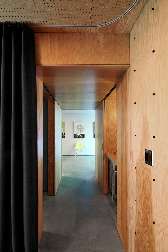 Cette image montre un couloir design de taille moyenne avec un mur marron, sol en béton ciré et un sol gris.