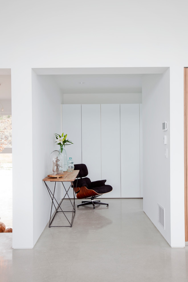 На фото: коридор среднего размера в современном стиле с белыми стенами, бетонным полом и серым полом