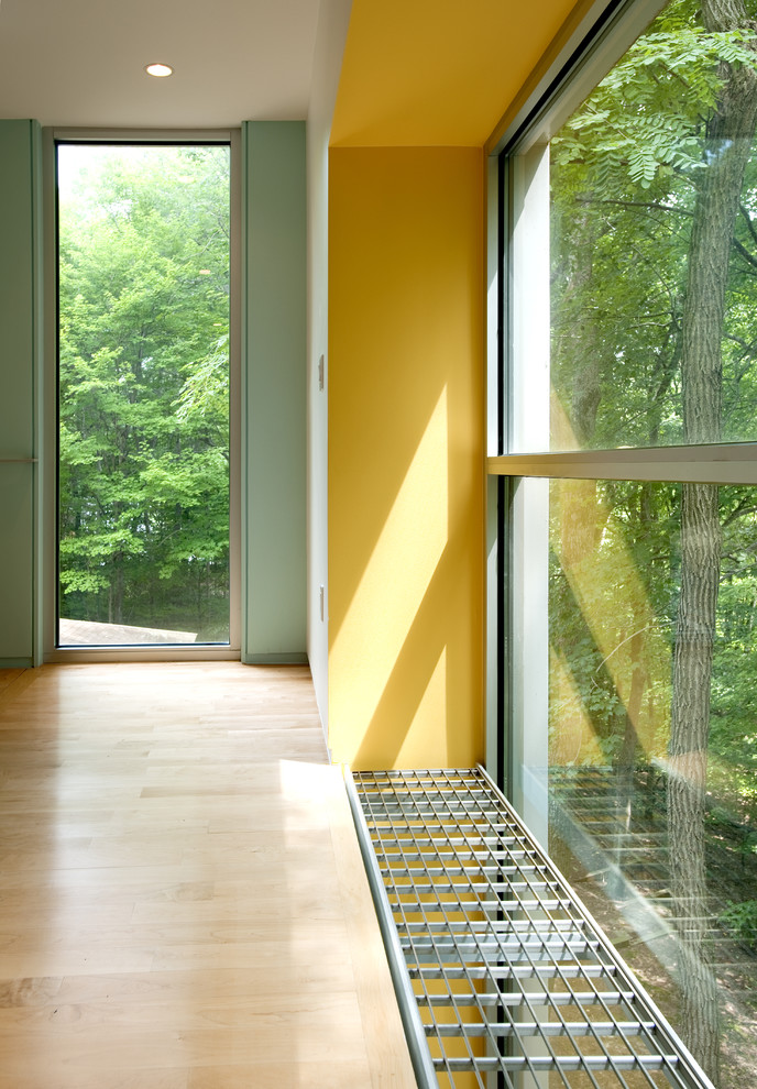Inspiration för moderna hallar, med gula väggar och ljust trägolv