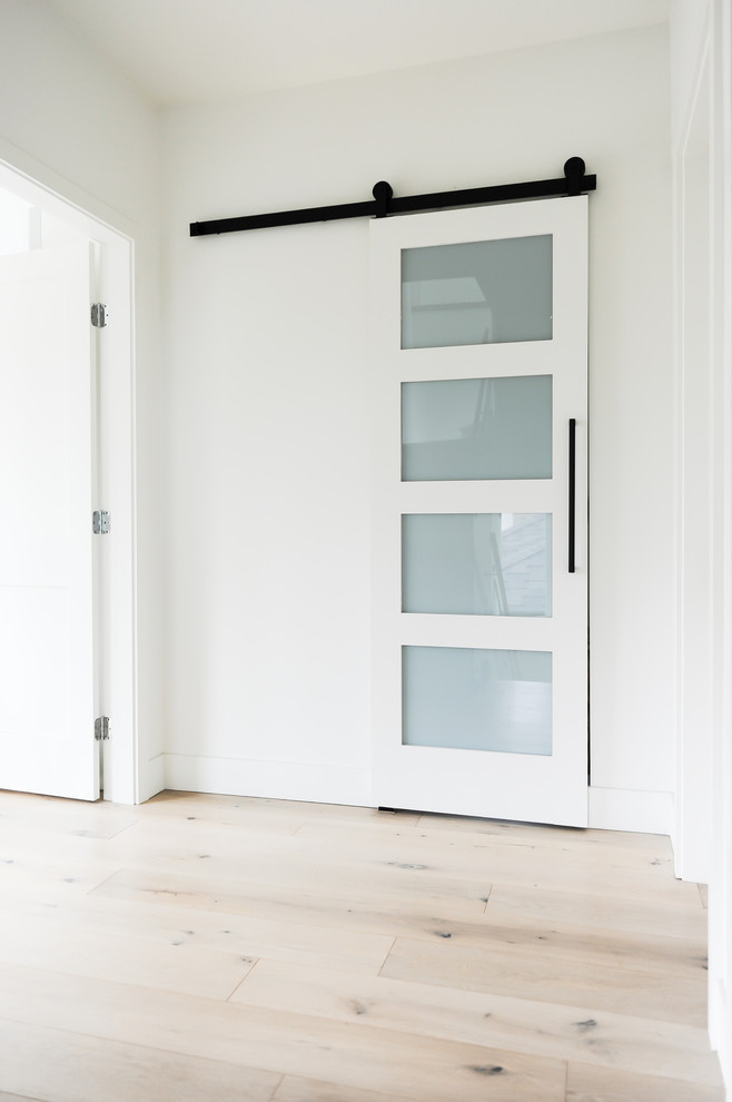 Esempio di un ingresso o corridoio minimalista con pareti bianche, parquet chiaro e pavimento beige