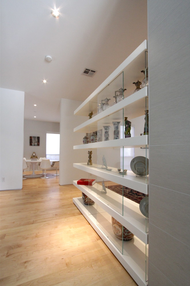 Example of a mid-sized minimalist light wood floor hallway design in Houston with white walls