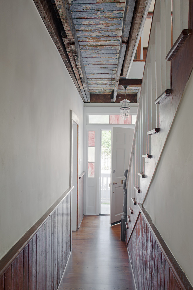 Immagine di un piccolo ingresso o corridoio country con pareti bianche, pavimento in legno massello medio e pavimento marrone