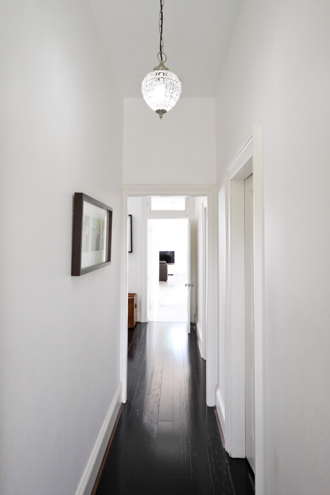 Immagine di un ingresso o corridoio contemporaneo con pareti bianche, pavimento in legno verniciato e pavimento nero