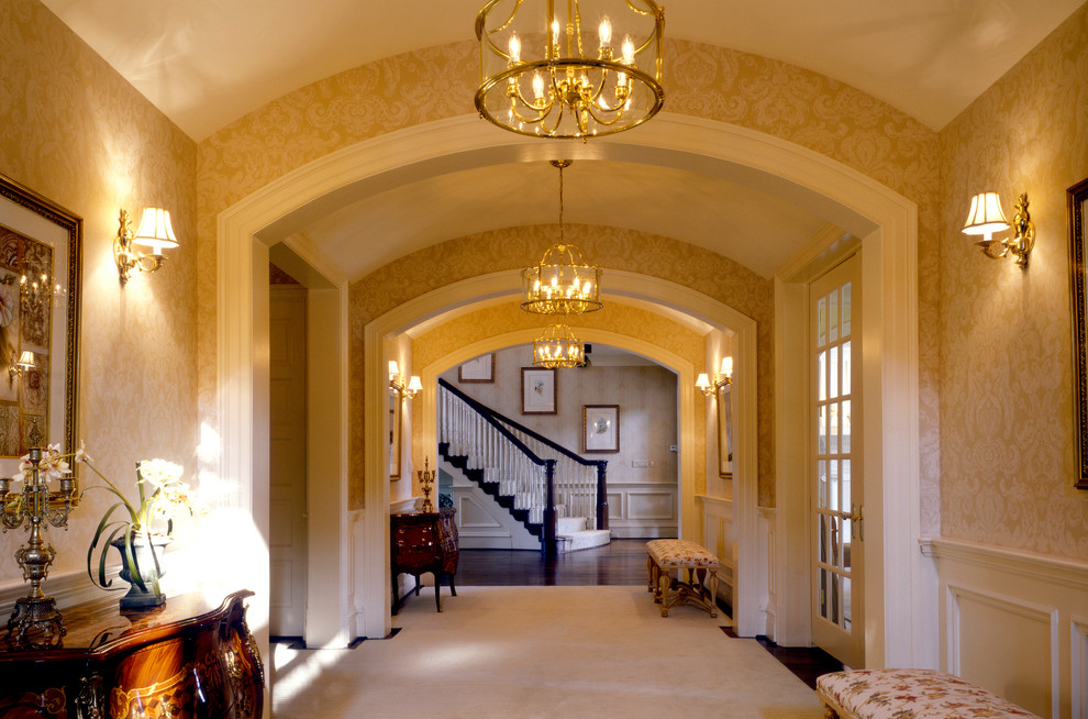 На фото: огромный коридор в классическом стиле с бежевыми стенами и паркетным полом среднего тона