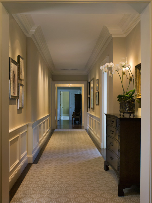 На фото: большой коридор в классическом стиле с бежевыми стенами, ковровым покрытием и коричневым полом