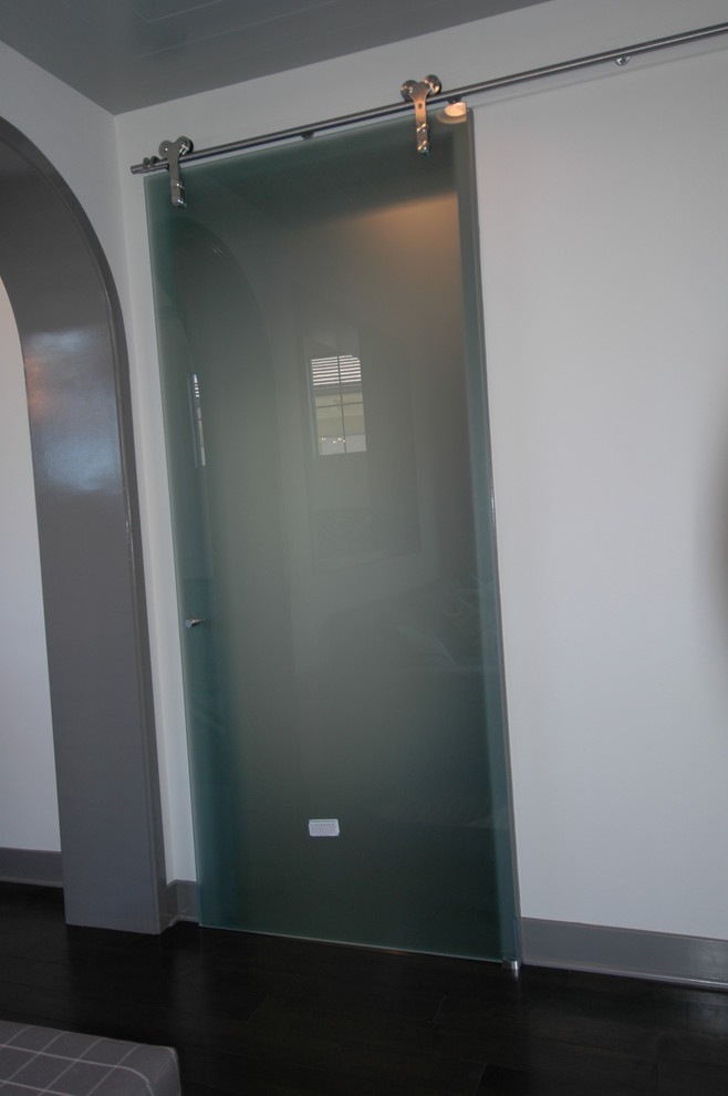 Cette image montre un couloir minimaliste de taille moyenne avec un mur blanc et parquet foncé.