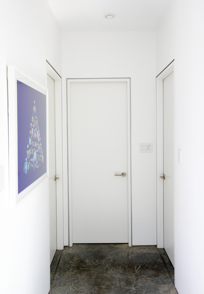 На фото: коридор среднего размера в стиле модернизм с белыми стенами, бетонным полом и серым полом