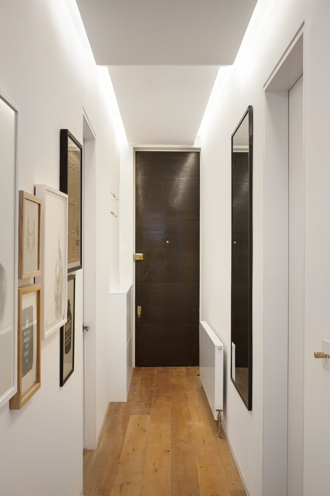 Idées déco pour un couloir contemporain de taille moyenne avec un mur blanc et parquet foncé.