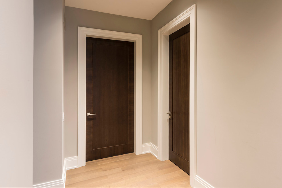 Cette photo montre un couloir tendance de taille moyenne avec un mur gris, parquet clair et un sol beige.