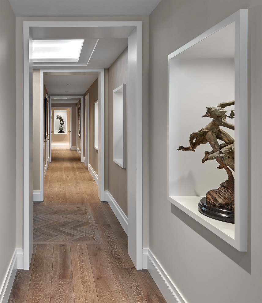 Cette photo montre un couloir chic avec un mur beige, un sol en bois brun et un sol marron.