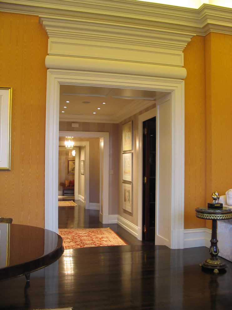 Imagen de recibidores y pasillos actuales de tamaño medio con parades naranjas, suelo de madera oscura y suelo marrón