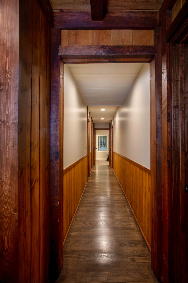 Ejemplo de recibidores y pasillos rústicos pequeños con paredes marrones, suelo de madera en tonos medios, suelo marrón, vigas vistas y panelado