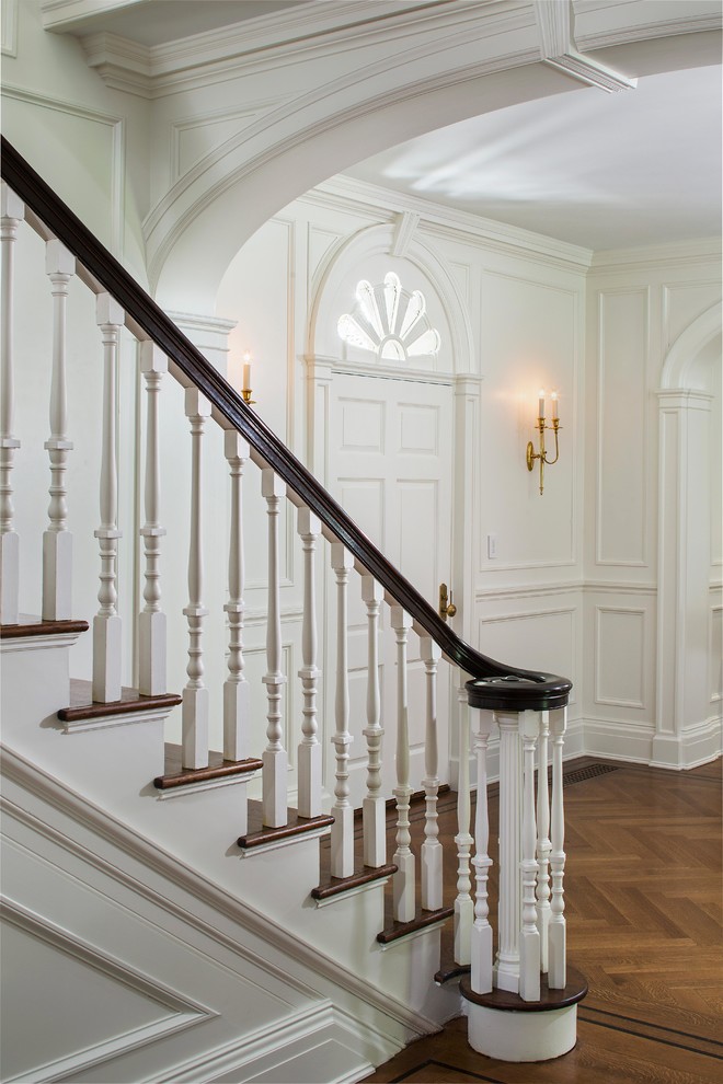 На фото: огромный коридор в классическом стиле с белыми стенами, паркетным полом среднего тона и коричневым полом с