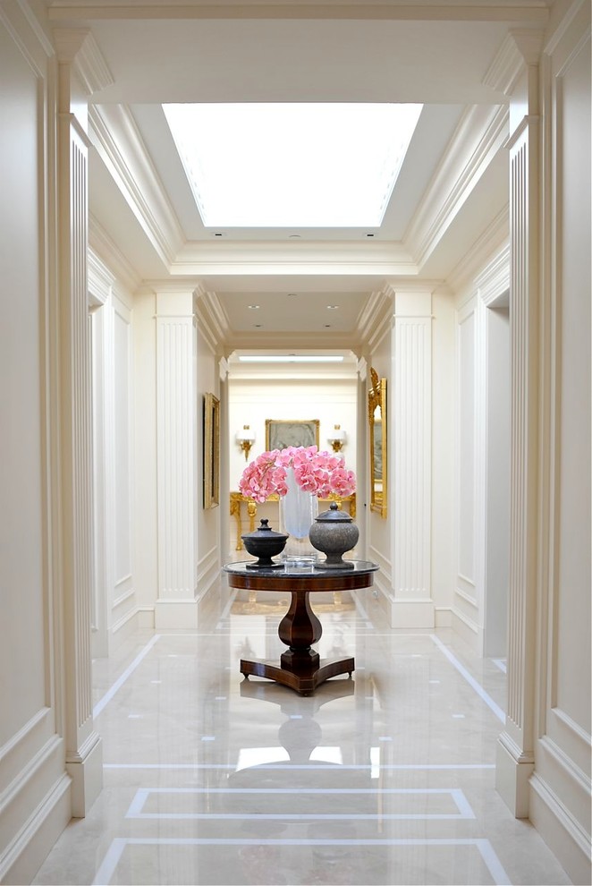 Стильный дизайн: огромный коридор в классическом стиле с белыми стенами и мраморным полом - последний тренд