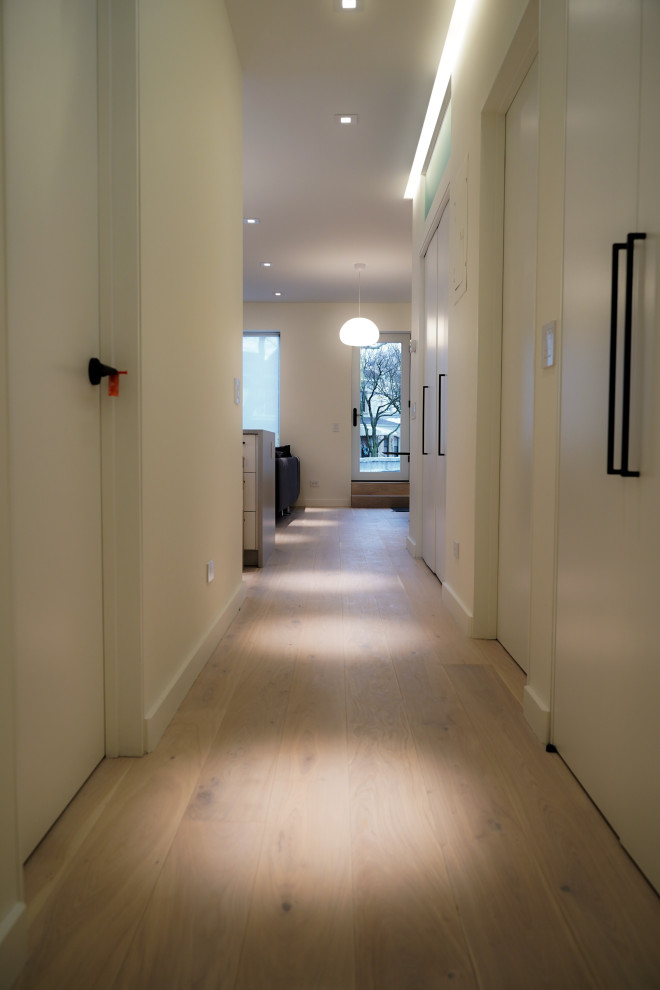 Idee per un ingresso o corridoio contemporaneo di medie dimensioni con pareti bianche, parquet chiaro e pavimento marrone