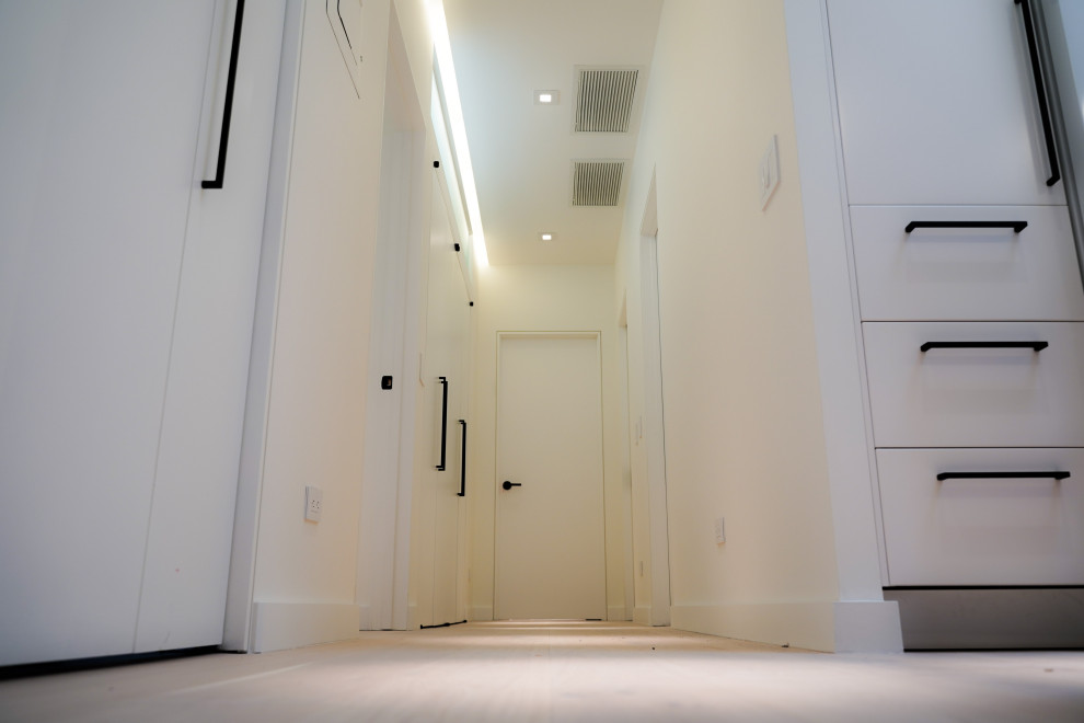 Idées déco pour un couloir contemporain de taille moyenne avec un mur blanc, parquet clair et un sol marron.
